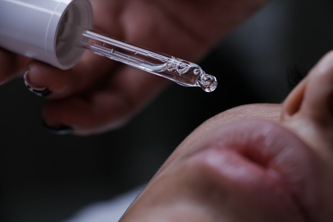Glaspipett med serum hålls nära en persons ansikte